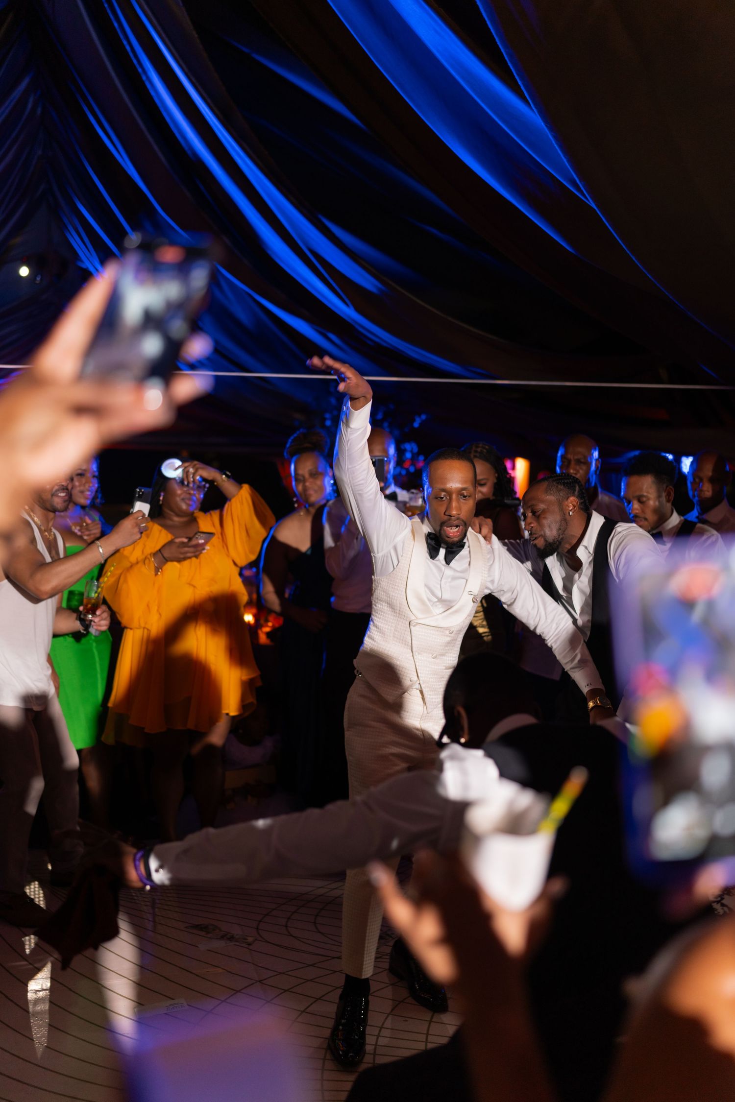 Wedding reception dance party with blue lighting and guests celebrating on the dance floor.