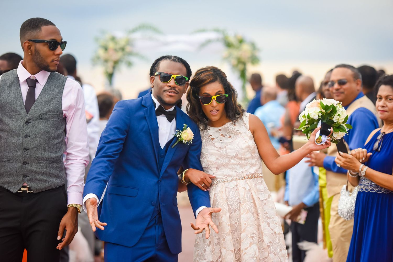 Outdoor wedding ceremony with guests in summer attire and bright blue skies.