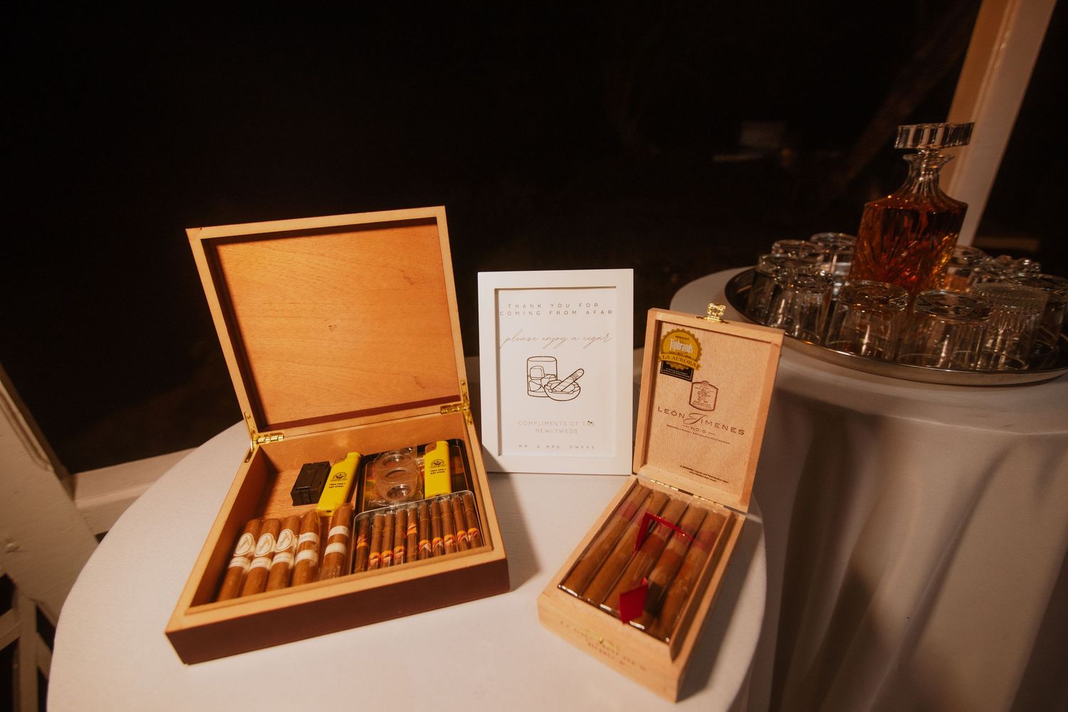 Wooden cigar boxes and spirits displayed on elegant wedding reception table.