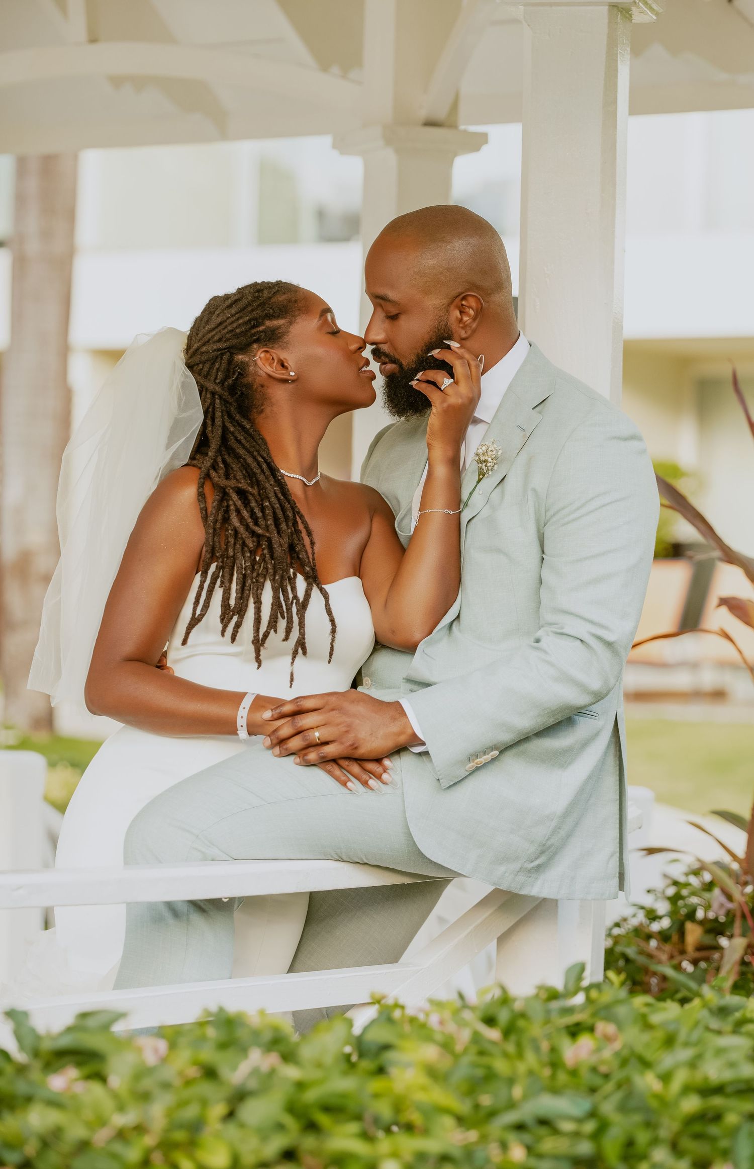 An intimate wedding portrait session under a white gazebo surrounded by lush greenery.
