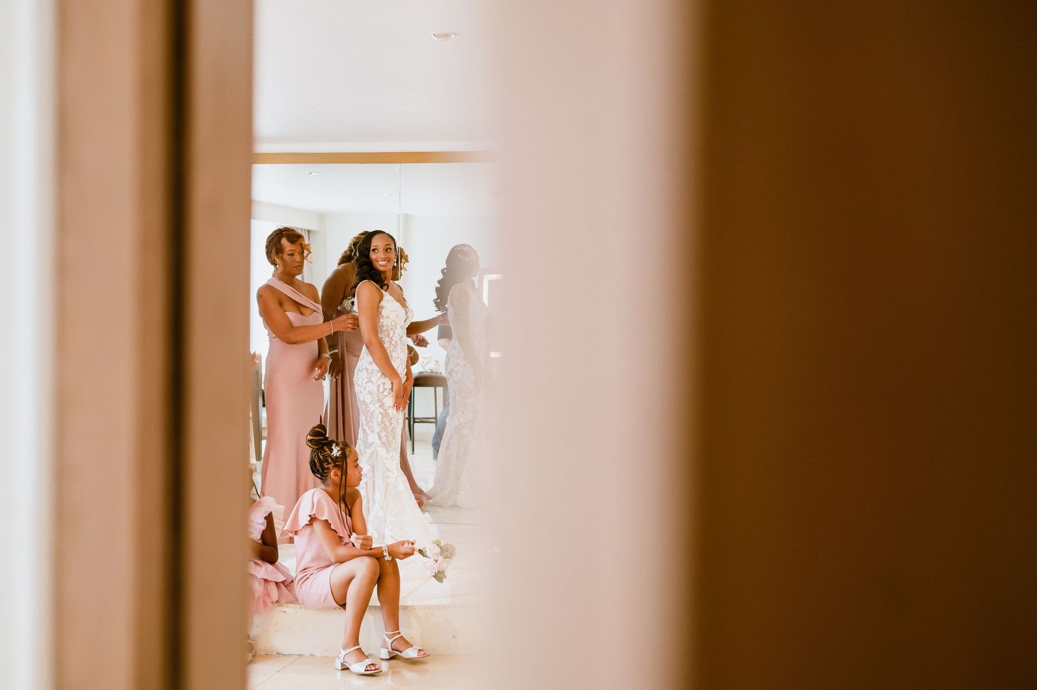 Candid shot of wedding party members dancing and celebrating in a bright room.