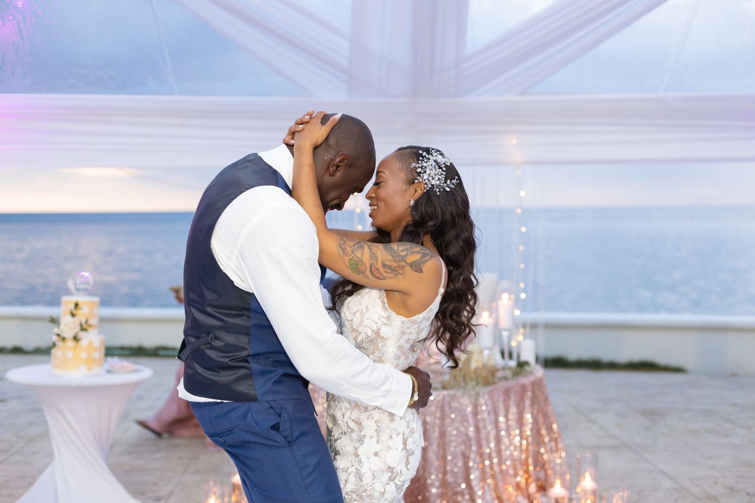 Romantic wedding reception scene with white drapes and ocean view in the background.