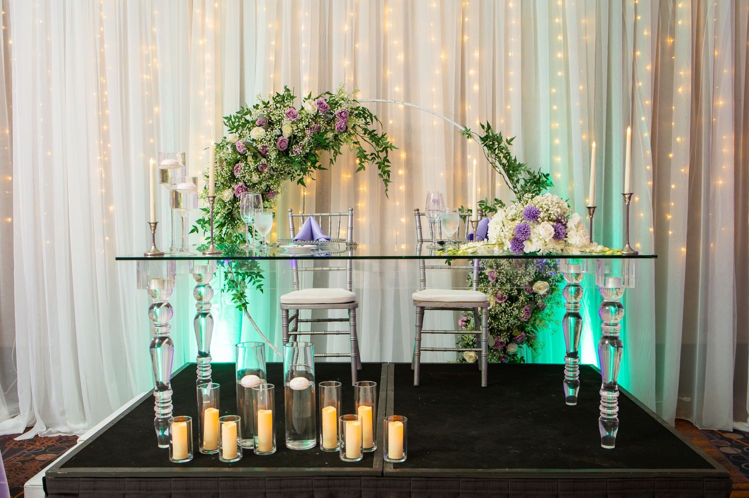 Wedding venue decor featuring white draping, greenery and romantic candle displays.