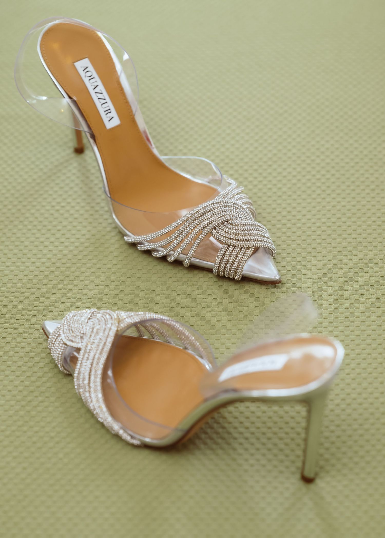 Elegant silver rhinestone bridal heels with intricate beaded detailing displayed on a light green background.