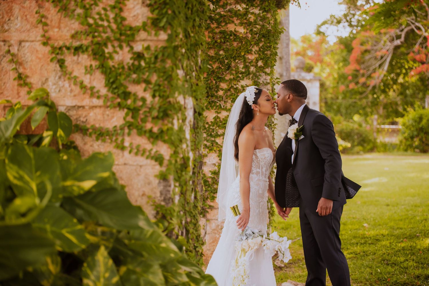 A beautiful outdoor wedding scene with the couple posing under trees in natural sunlight.