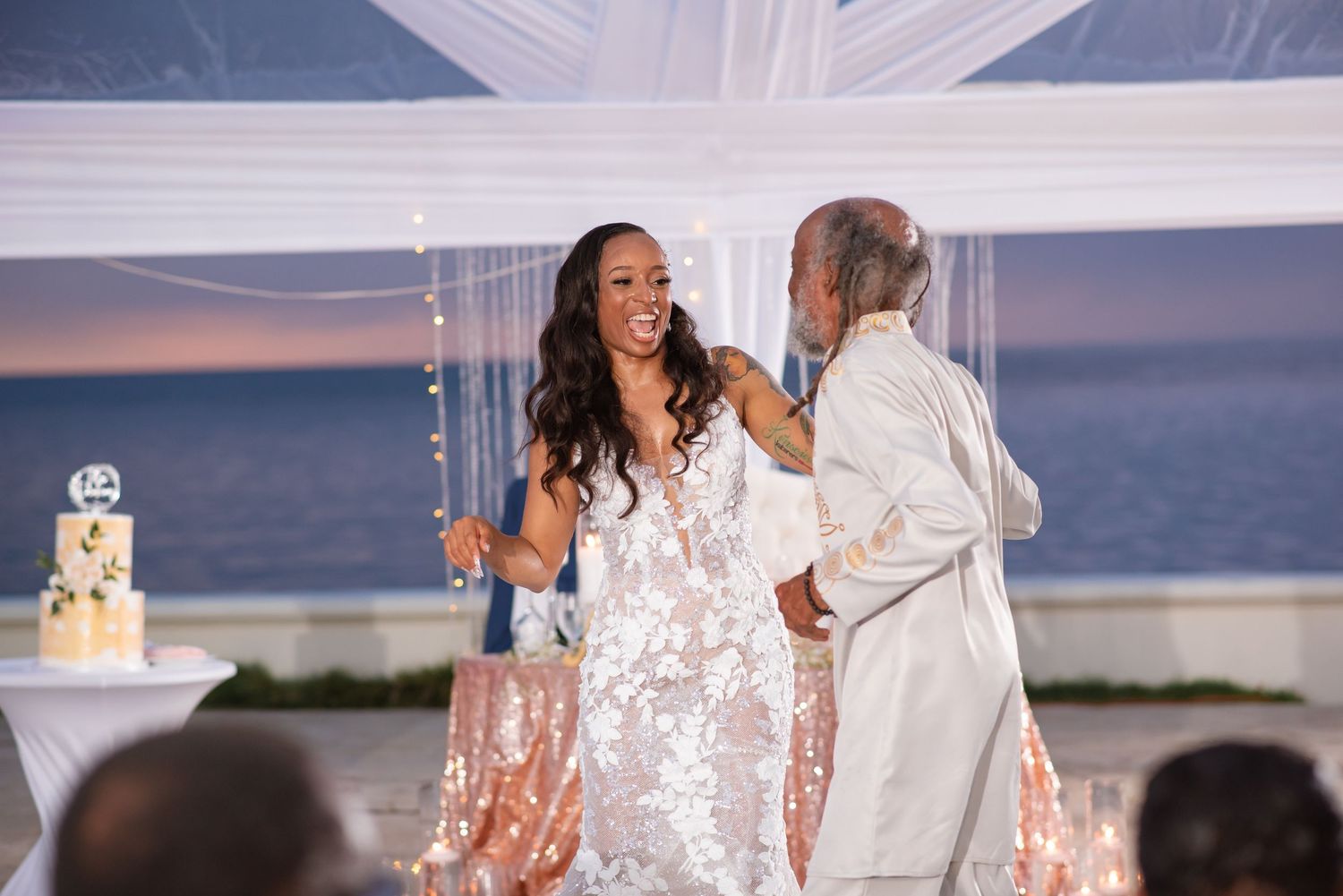 Elegant wedding reception setup with white draping and waterfront views.