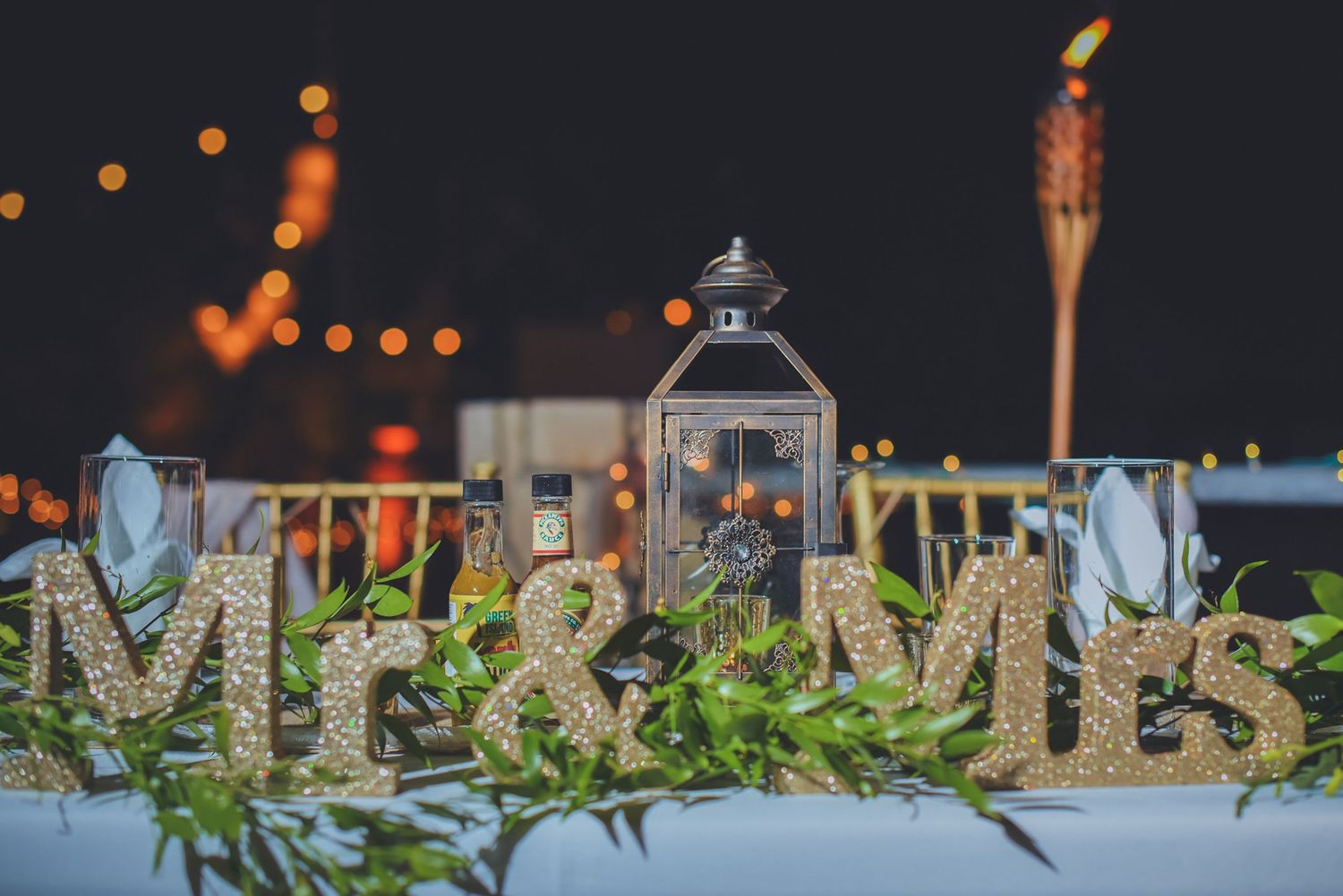 Wedding reception decor with lanterns, greenery and string lights creating a romantic ambiance.