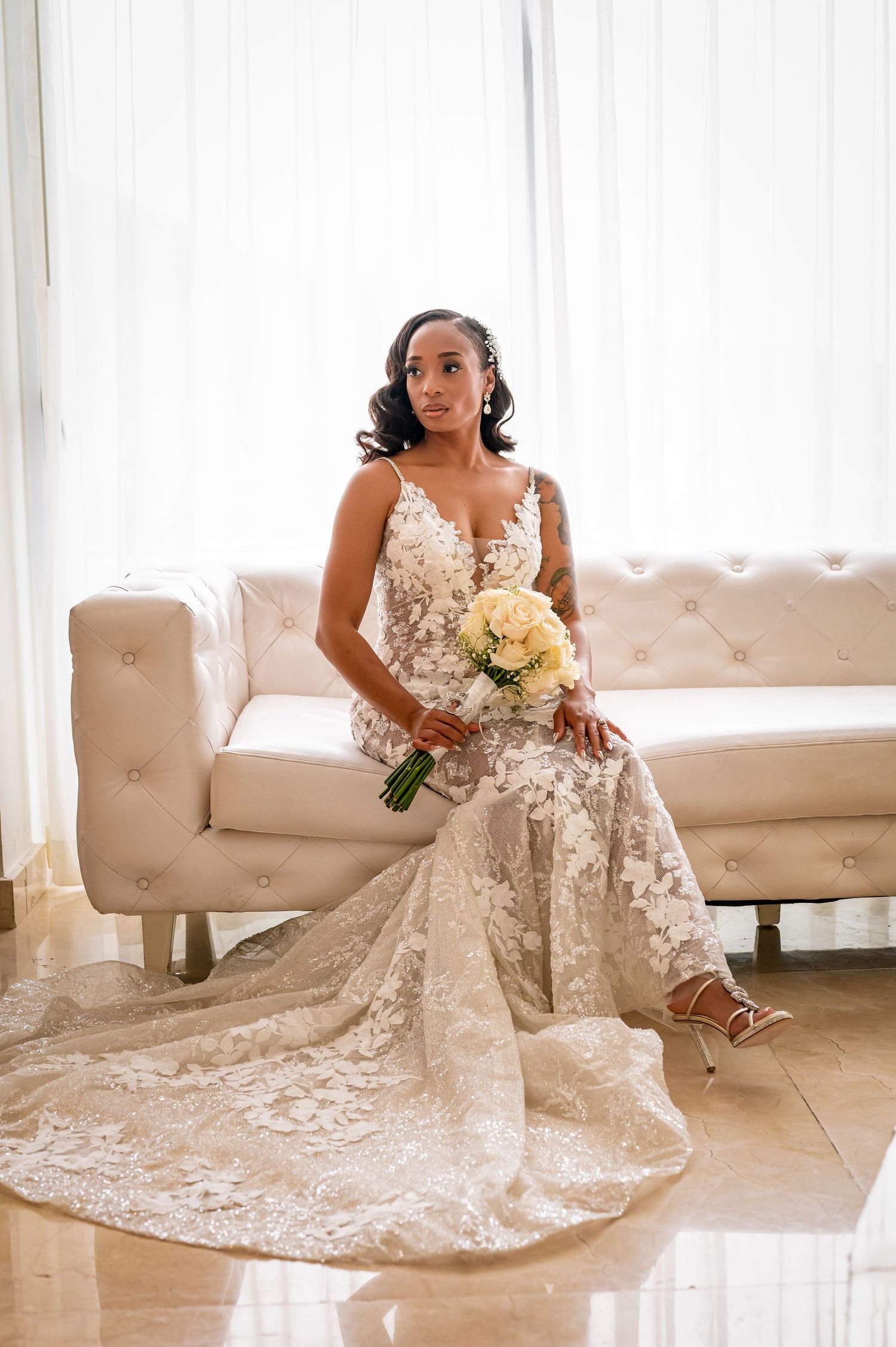 Full-length view of wedding dress with train spread across white couch.