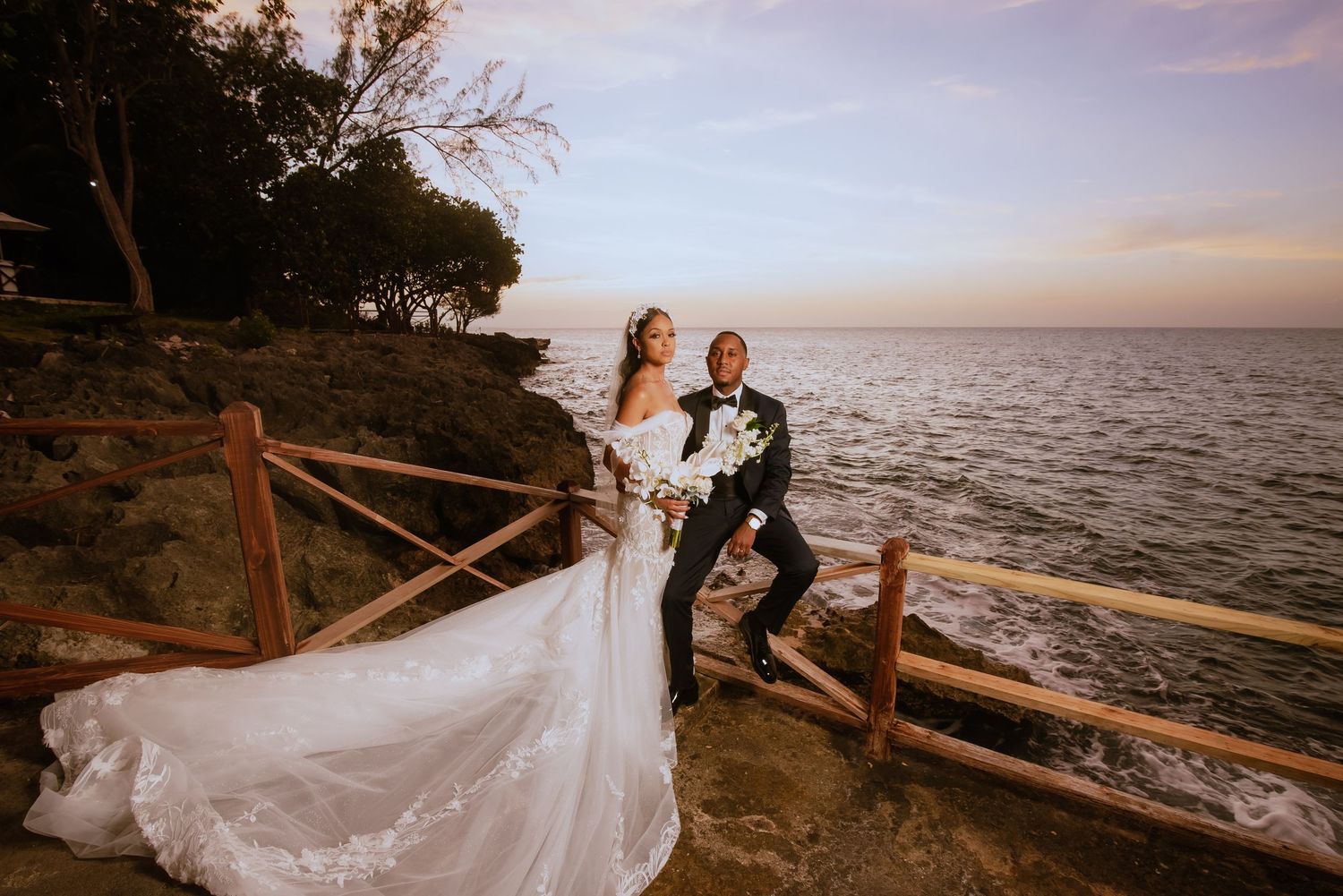 Sunset wedding photography session along a coastal wooden fence with ocean views.