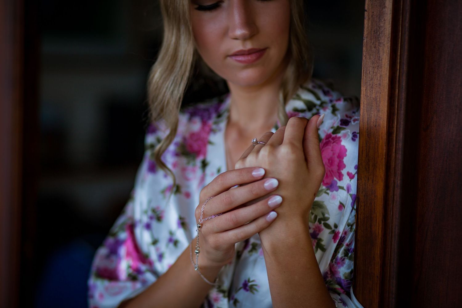 Woman in floral robe getting ready on her wedding day in natural light.