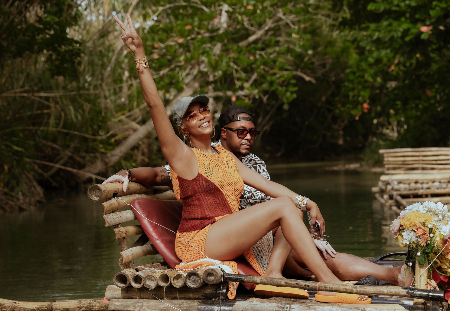 People relaxing on blankets near a peaceful waterfront surrounded by lush greenery.