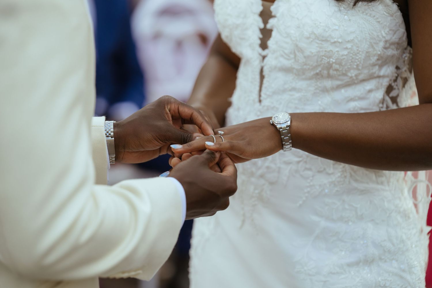 Close-up details of a wedding ceremony showing hands and white lace dress.