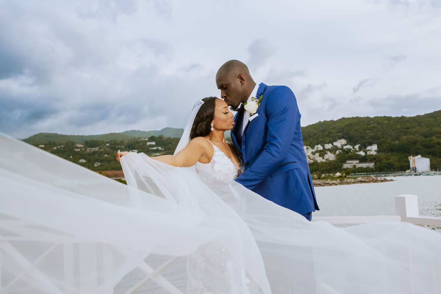Elegant waterfront wedding photos capture intimate moments against mountainous landscape.