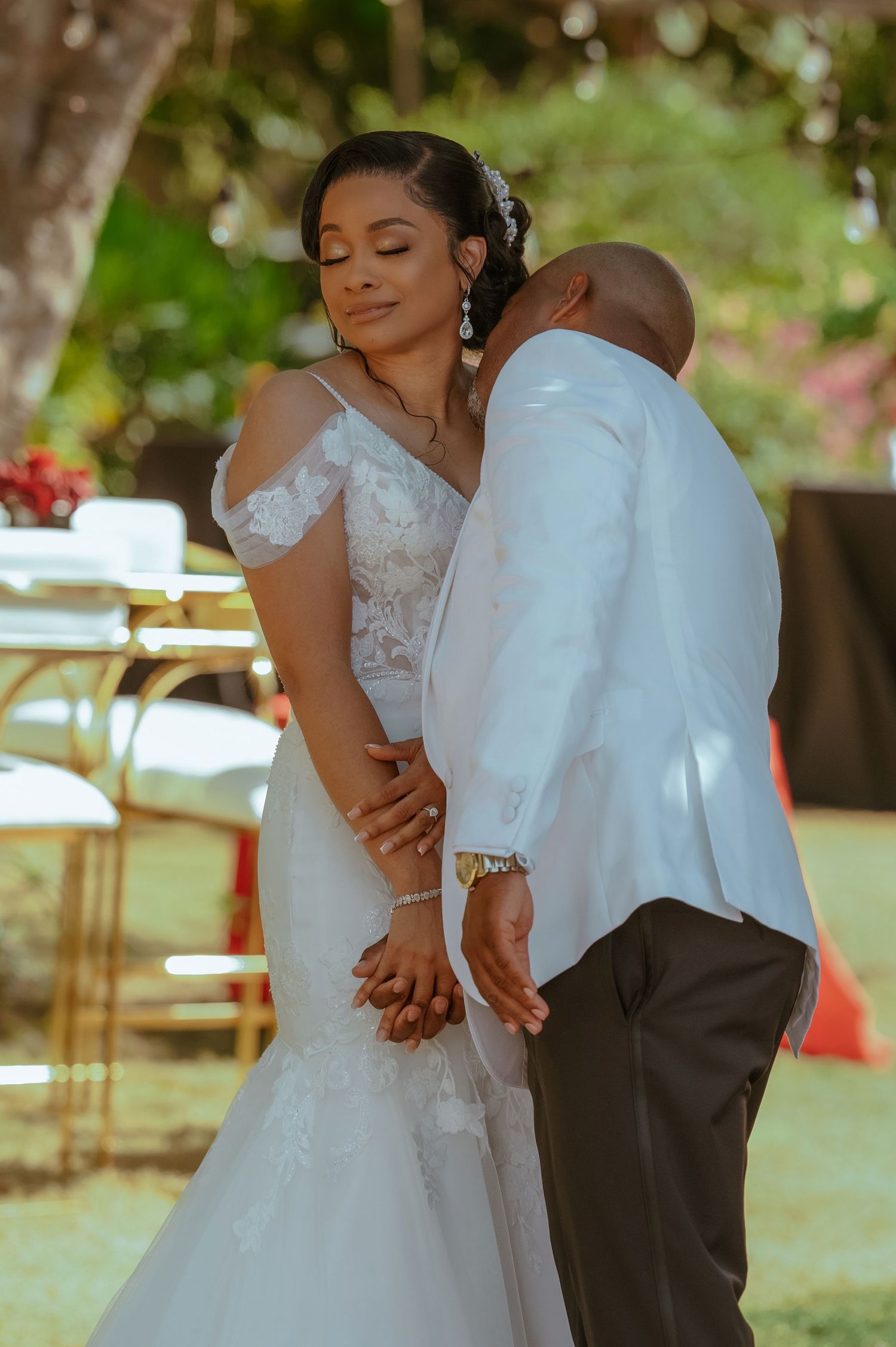 Tender moment between newlyweds during outdoor garden wedding reception.