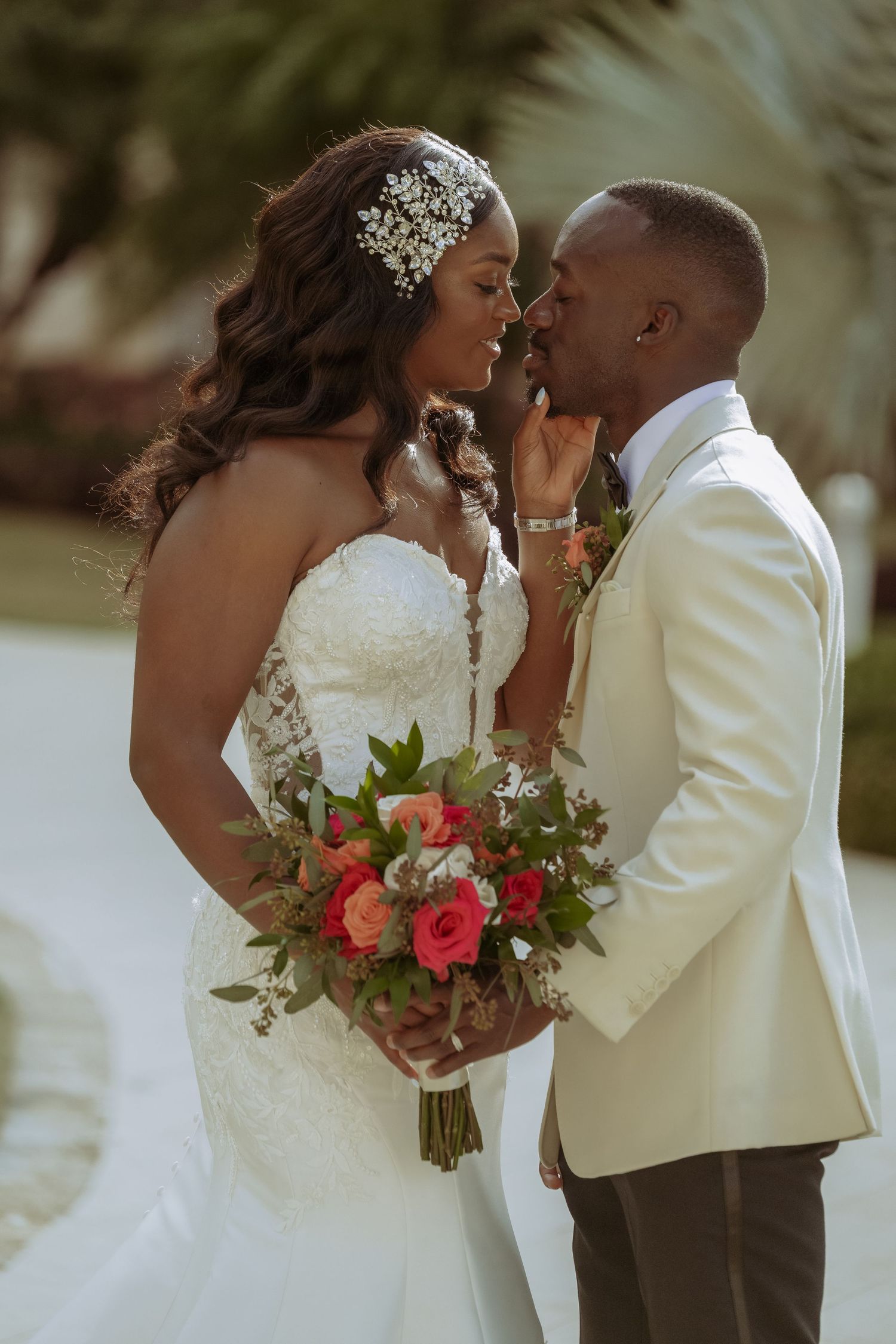 Romantic wedding moment with bride holding coral and green bouquet against tropical background.