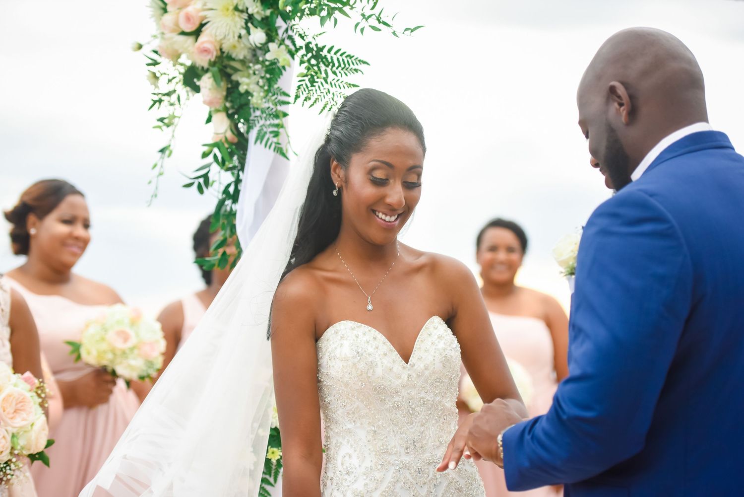 Emotional exchange during outdoor wedding ceremony under floral-decorated white tent.
