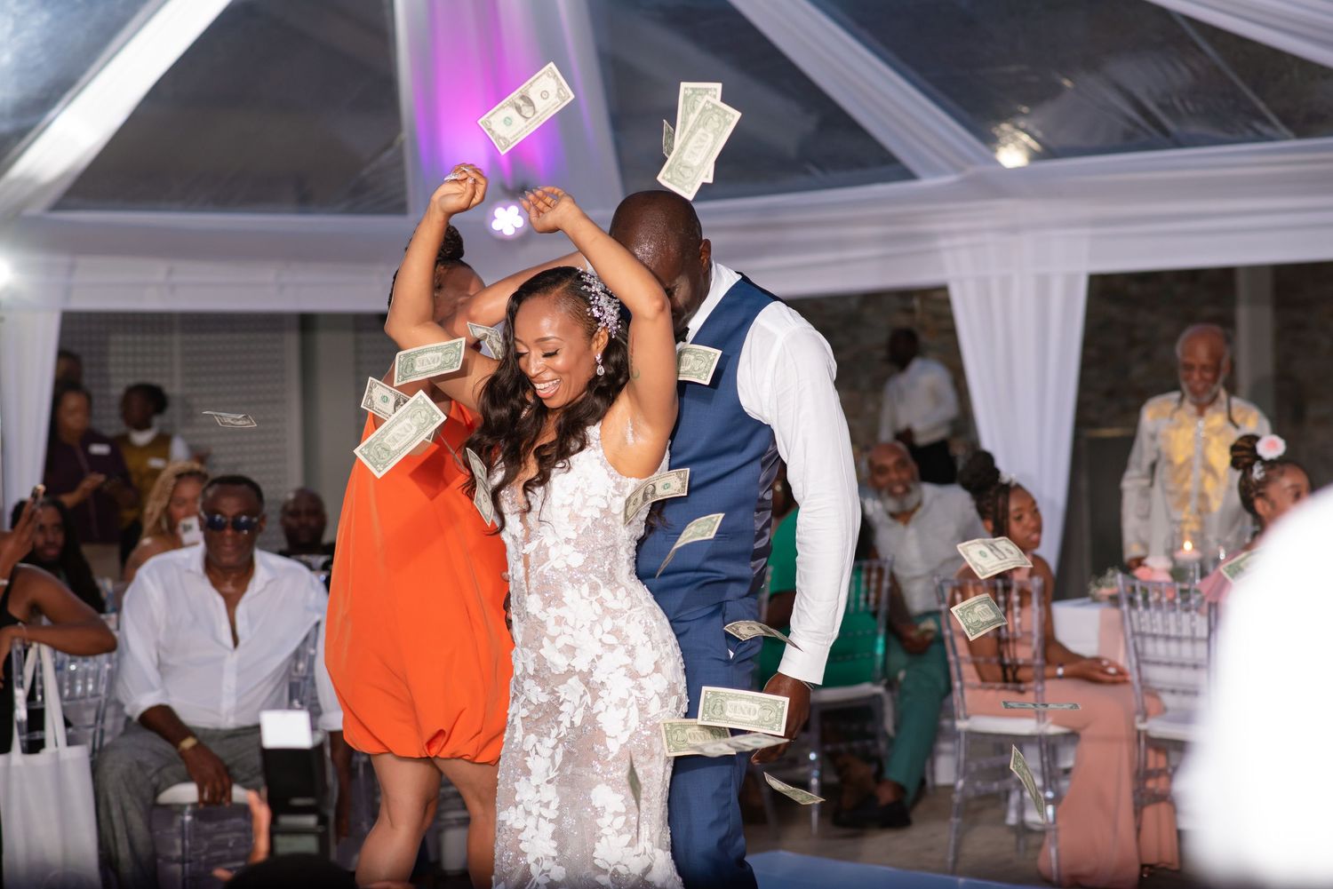Guests dancing and throwing dollar bills during a lively wedding celebration.