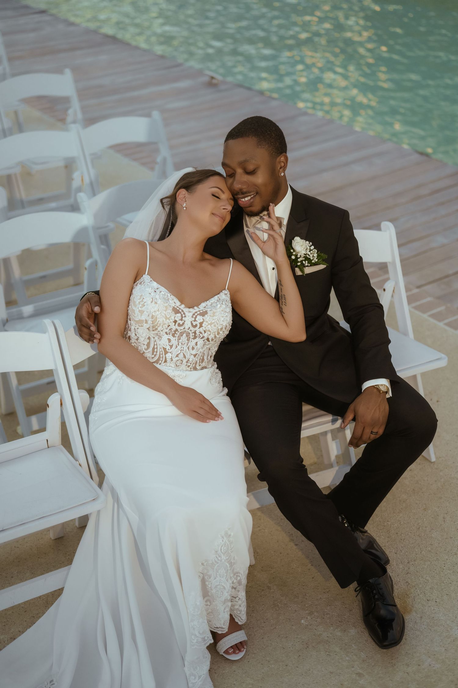 Candid wedding photos of couple sitting and laughing together by a poolside.