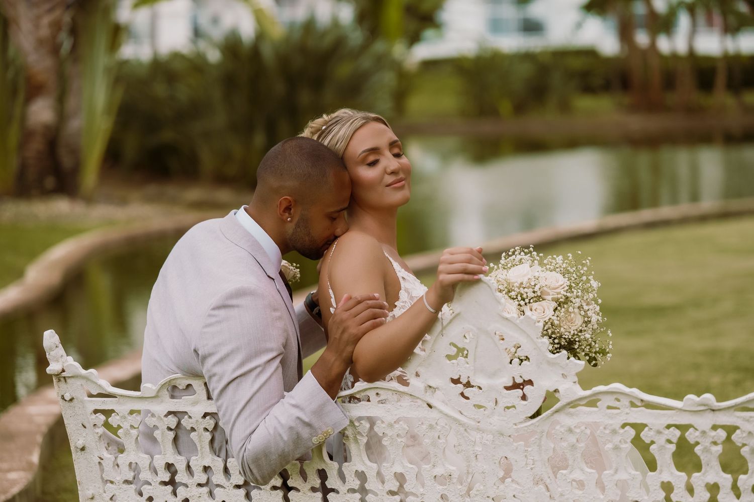 Romantic wedding couple sharing intimate moments by ornate white garden railings.
