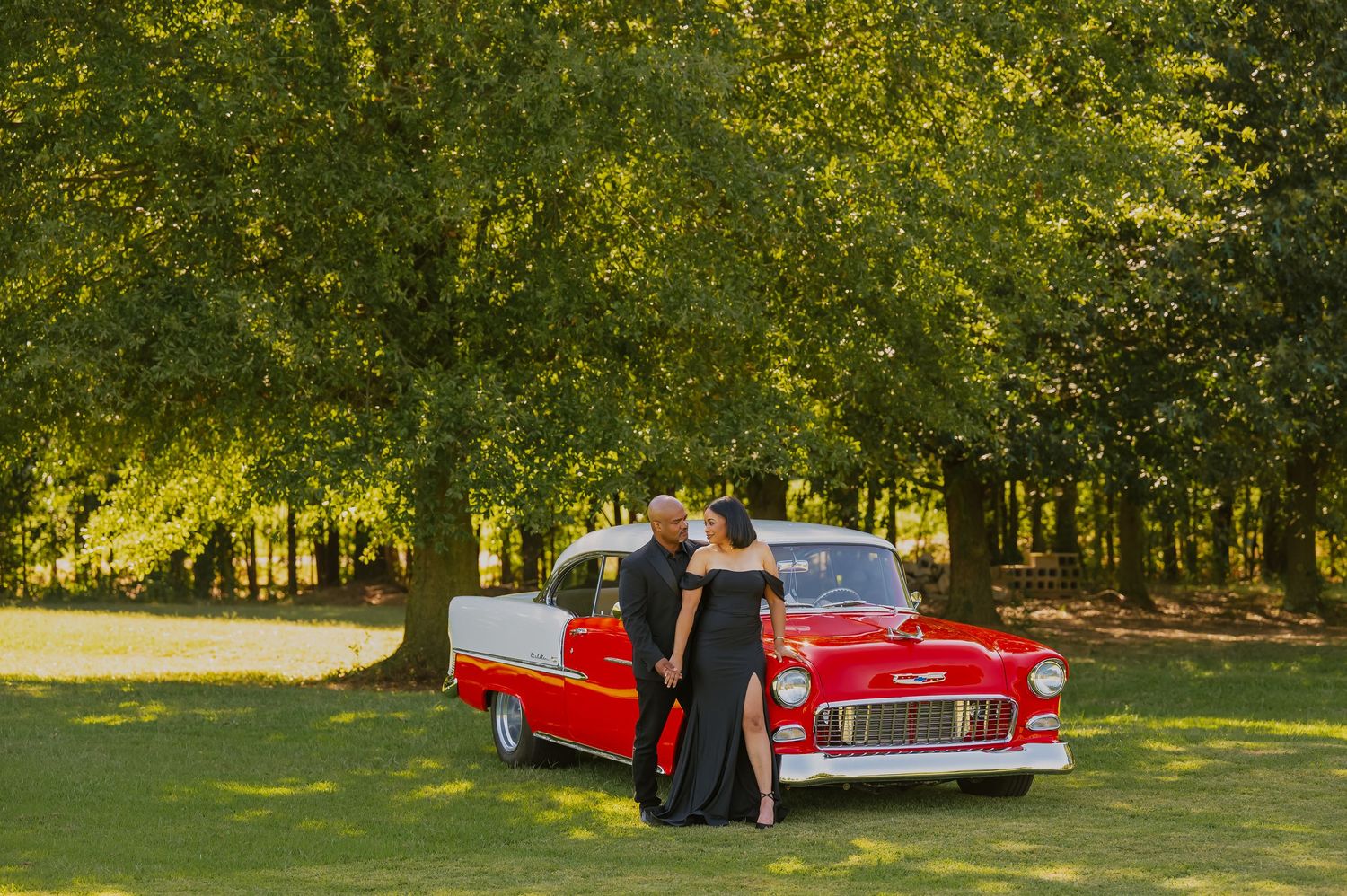 Classic red automobile photographed in park setting with natural lighting.