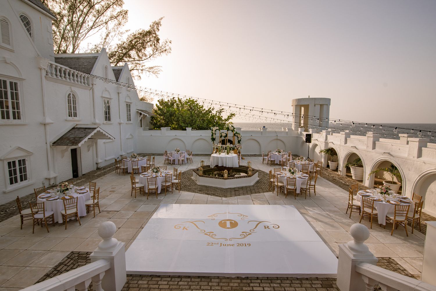 White Mediterranean villa venue with outdoor seating and ocean views at sunset.