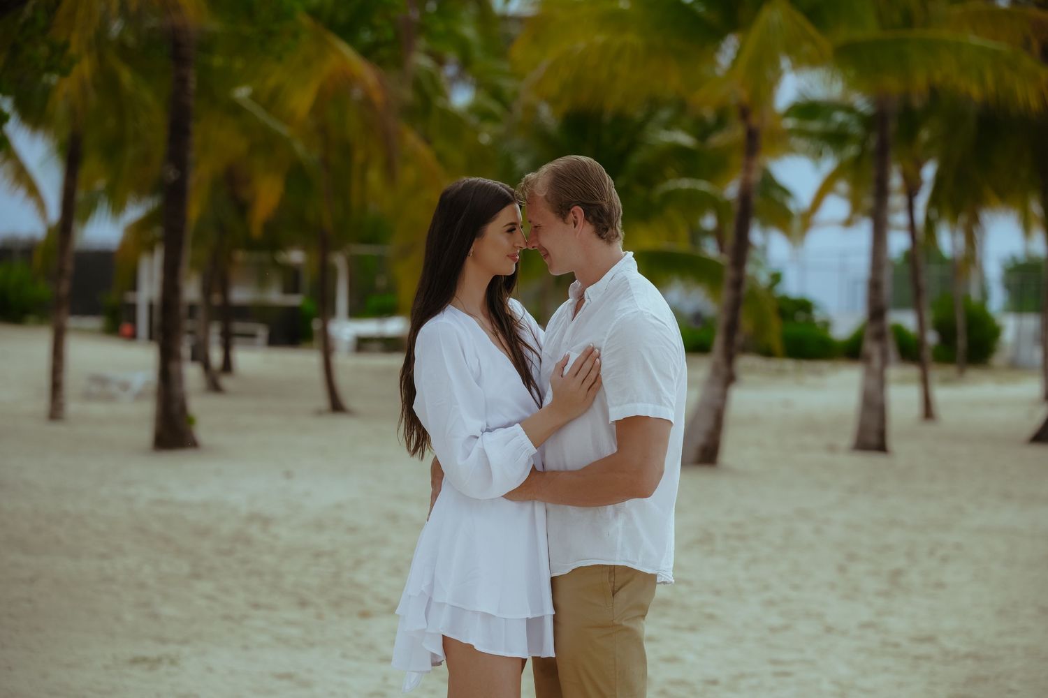 Romantic beach engagement photos with palm trees and ocean in the background.