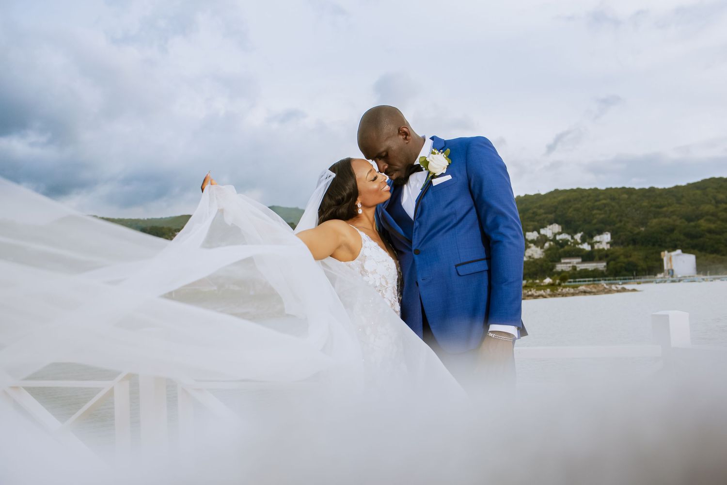 Scenic coastal wedding photography with dramatic cloudy sky and water backdrop.