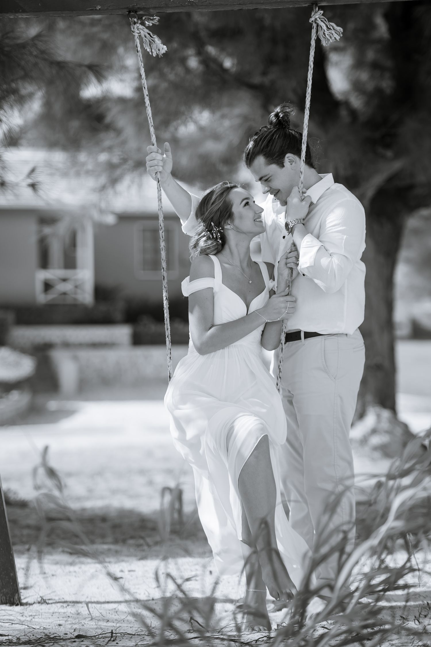 Romantic black and white photo series of couple on swing set during wedding photoshoot.