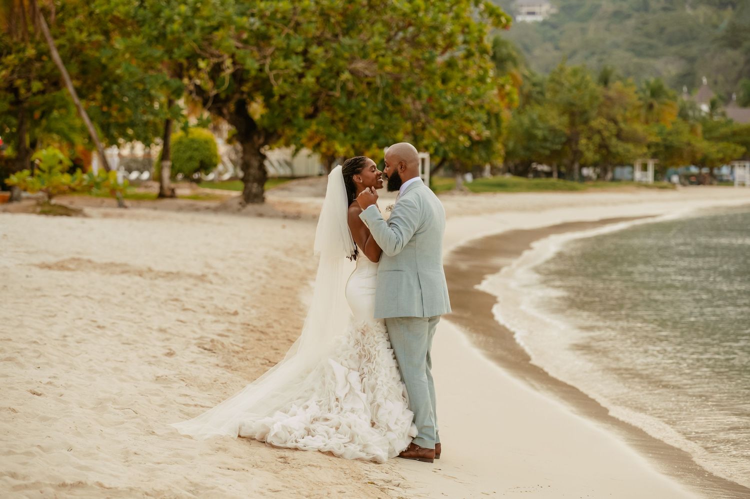 A romantic beachside wedding portrait with palm trees and ocean views.