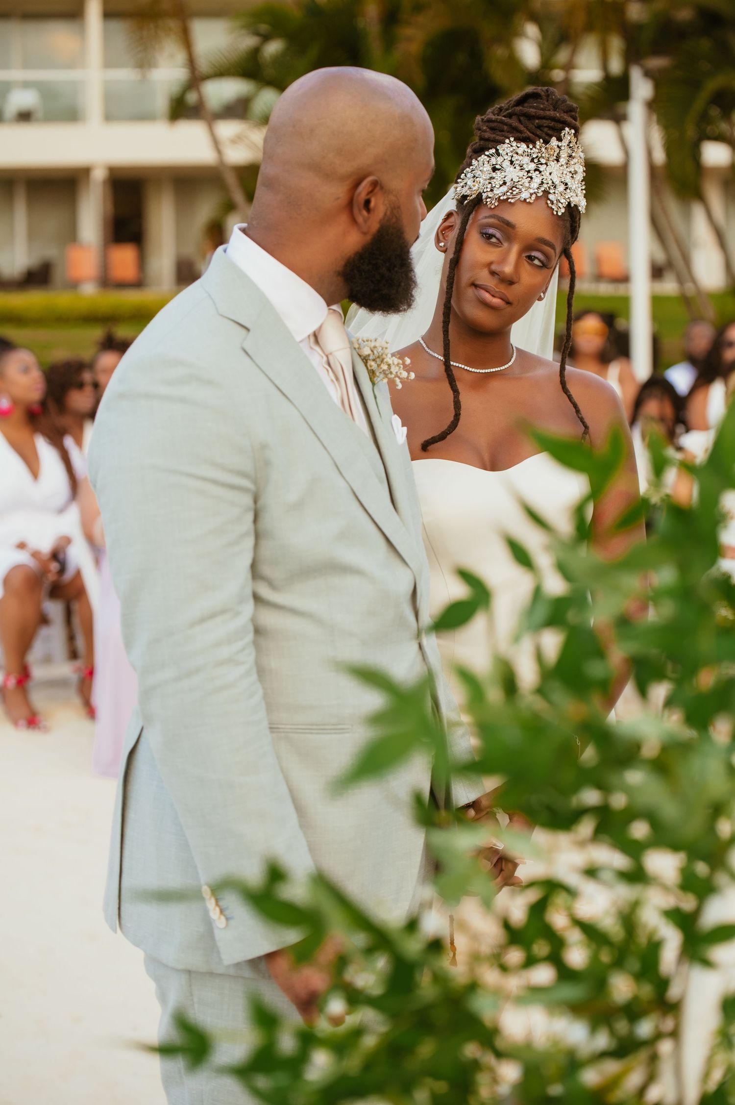 Bride and groom share a joyful moment during their beach wedding ceremony with palm trees in the background.
