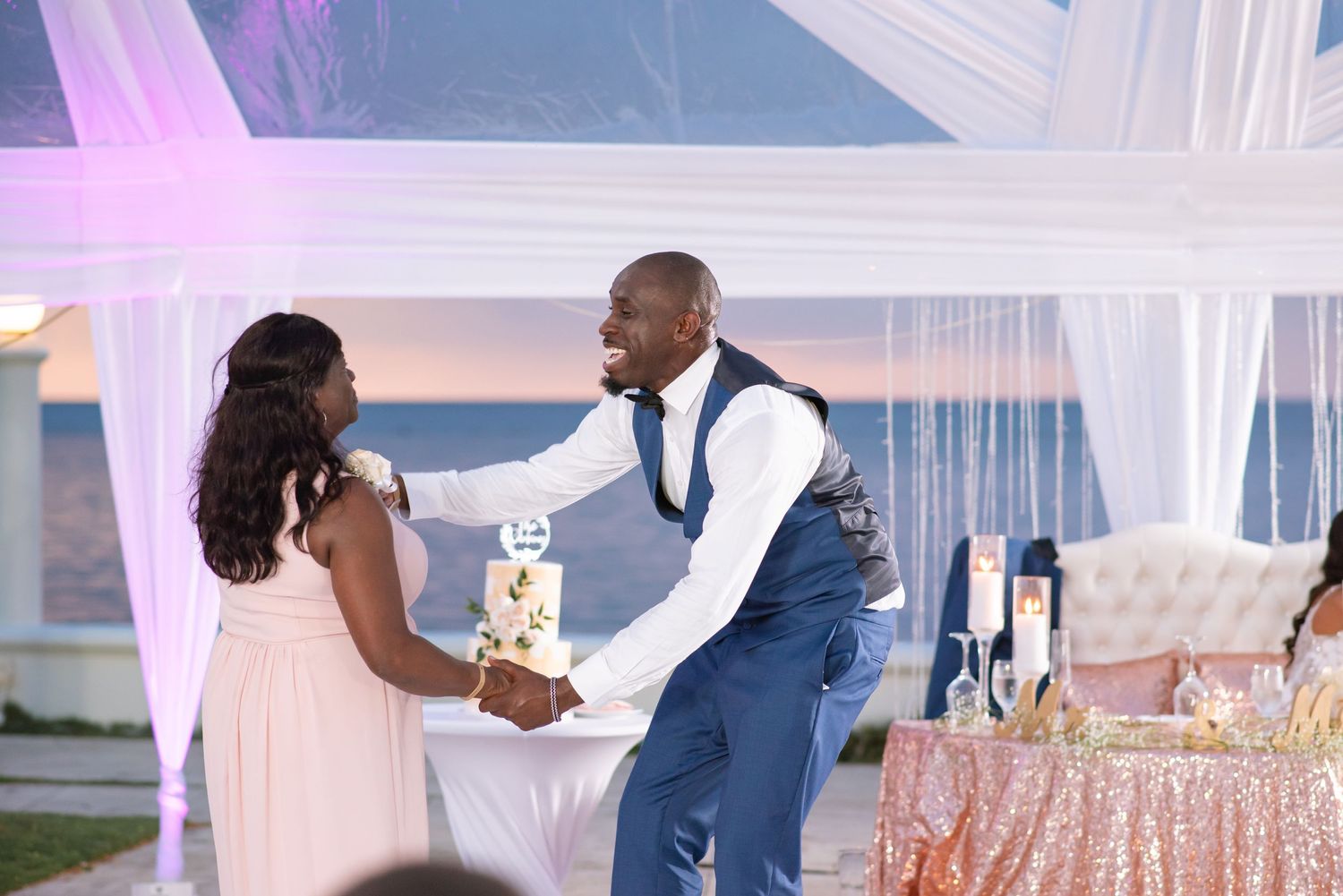 Purple-lit wedding reception venue with white drapes and celebratory atmosphere.