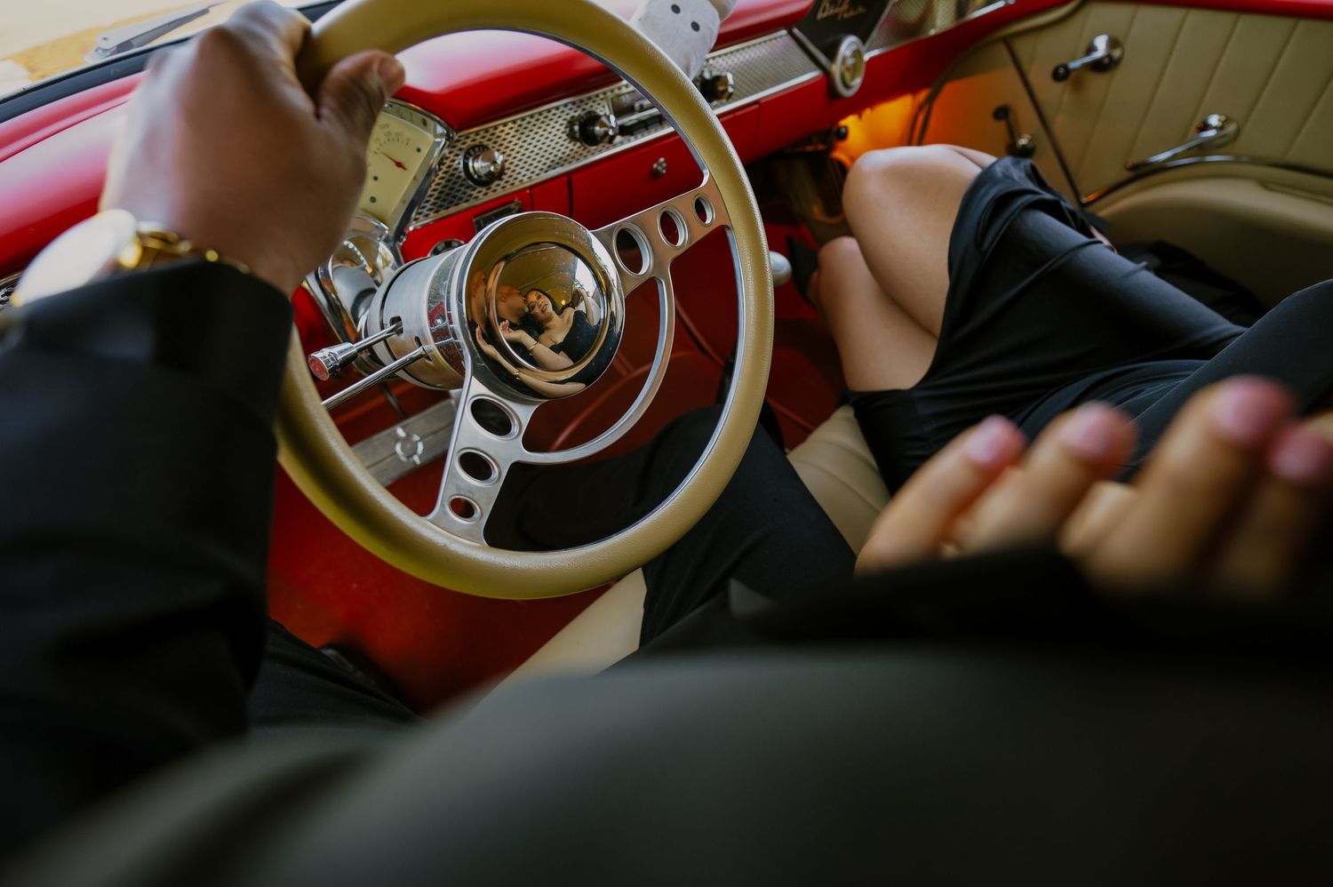 Close-up shot of hands on a vintage red steering wheel.