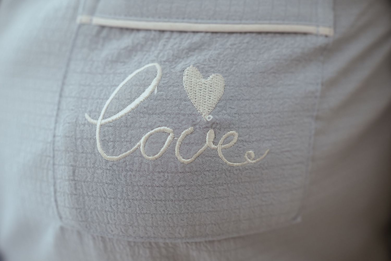 The word 'Love' embroidered with a heart on a light gray fabric pocket.