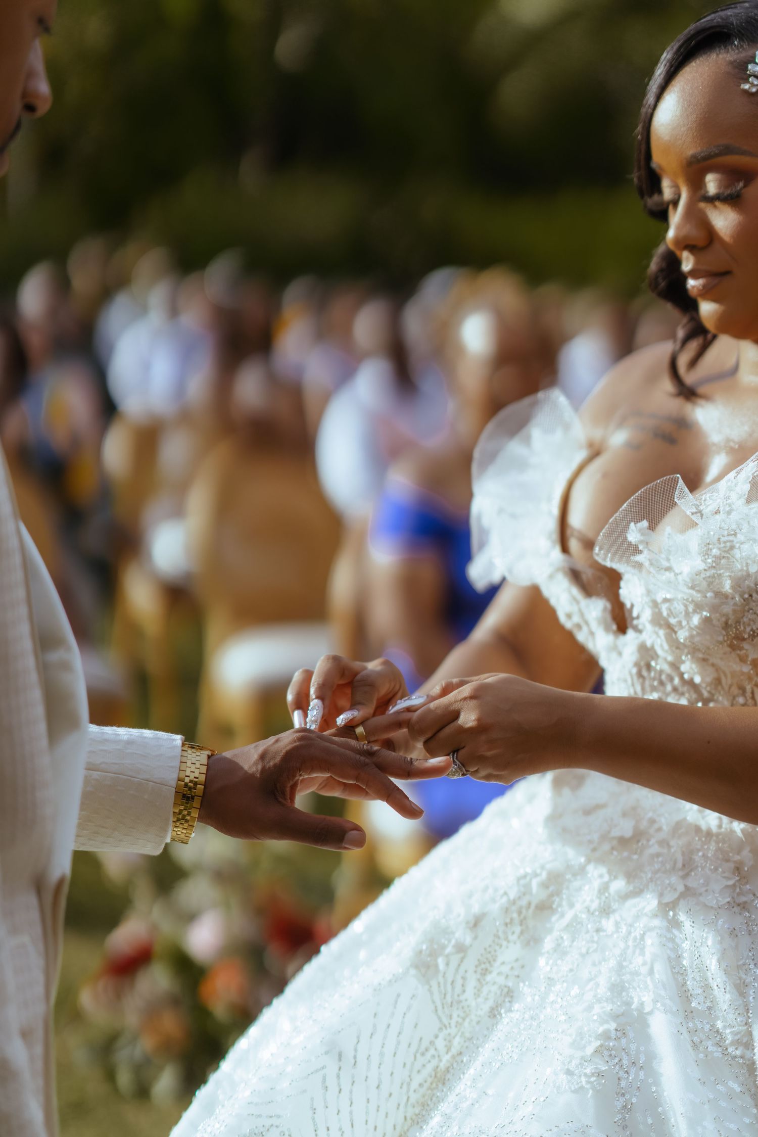 Close-up of wedding ring exchange ceremony with detailed lace dress in focus.