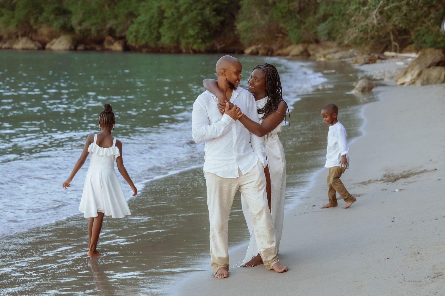 Family walking and playing together along a scenic beach shoreline.