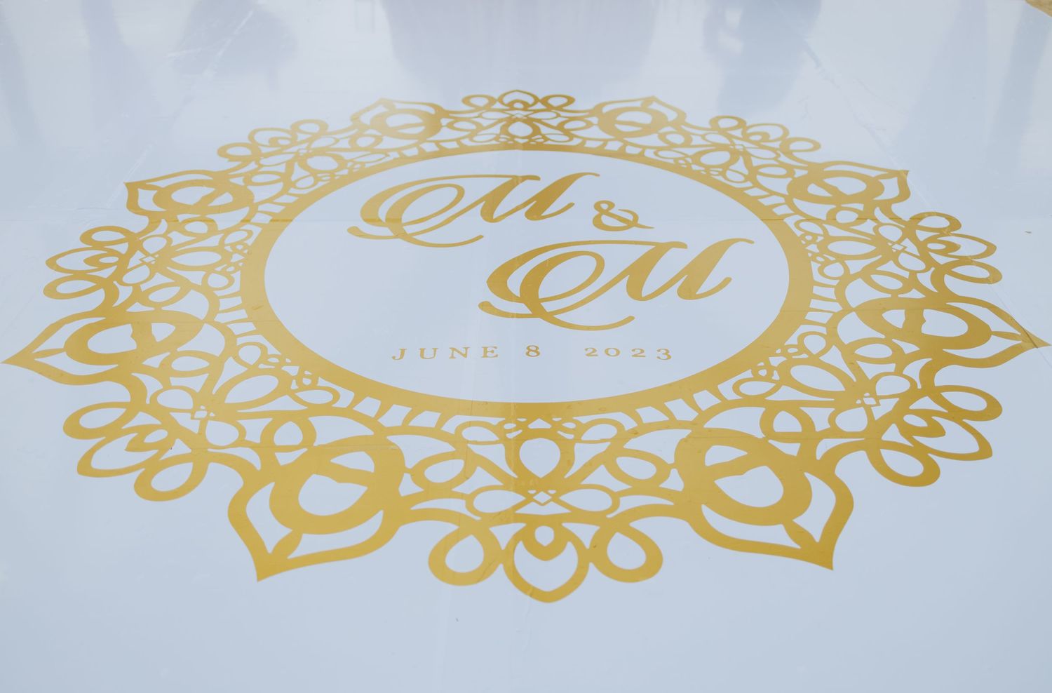 Gold ornate circular monogram designs on white dance floor.