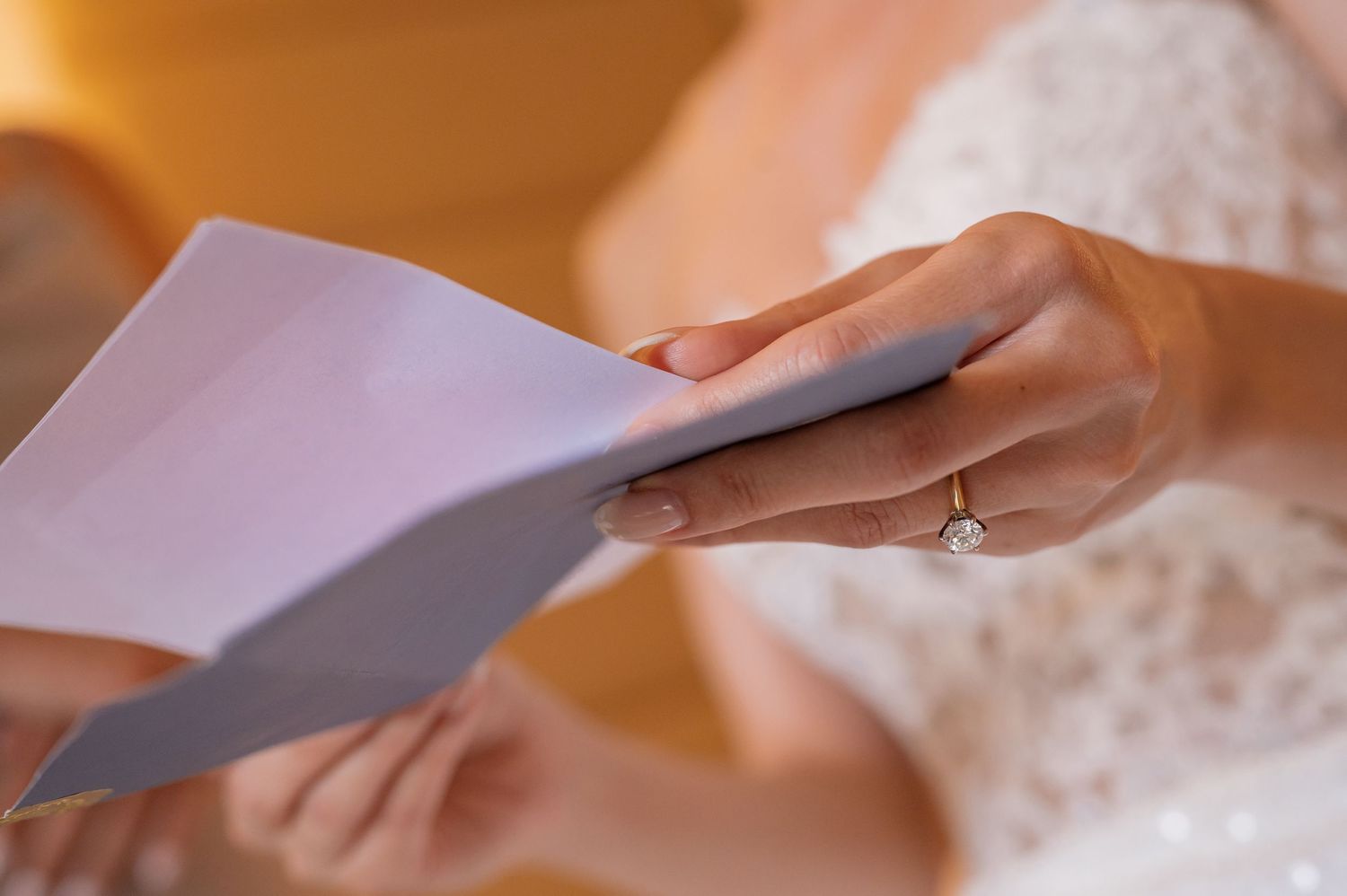 Close-up shot of hands holding paper in warm lighting.