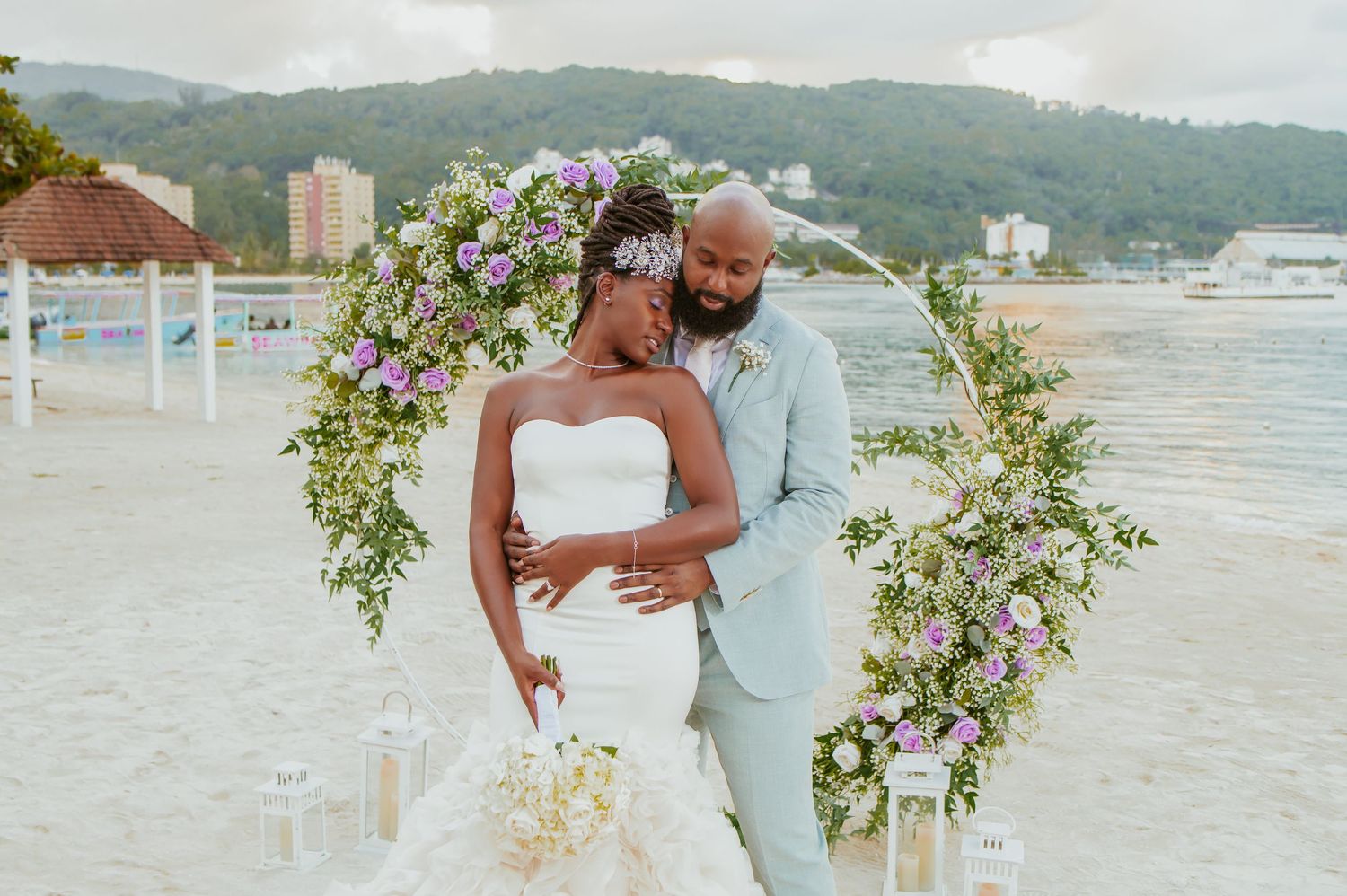 Intimate beachside wedding ceremony with floral decorations and mountain backdrop.