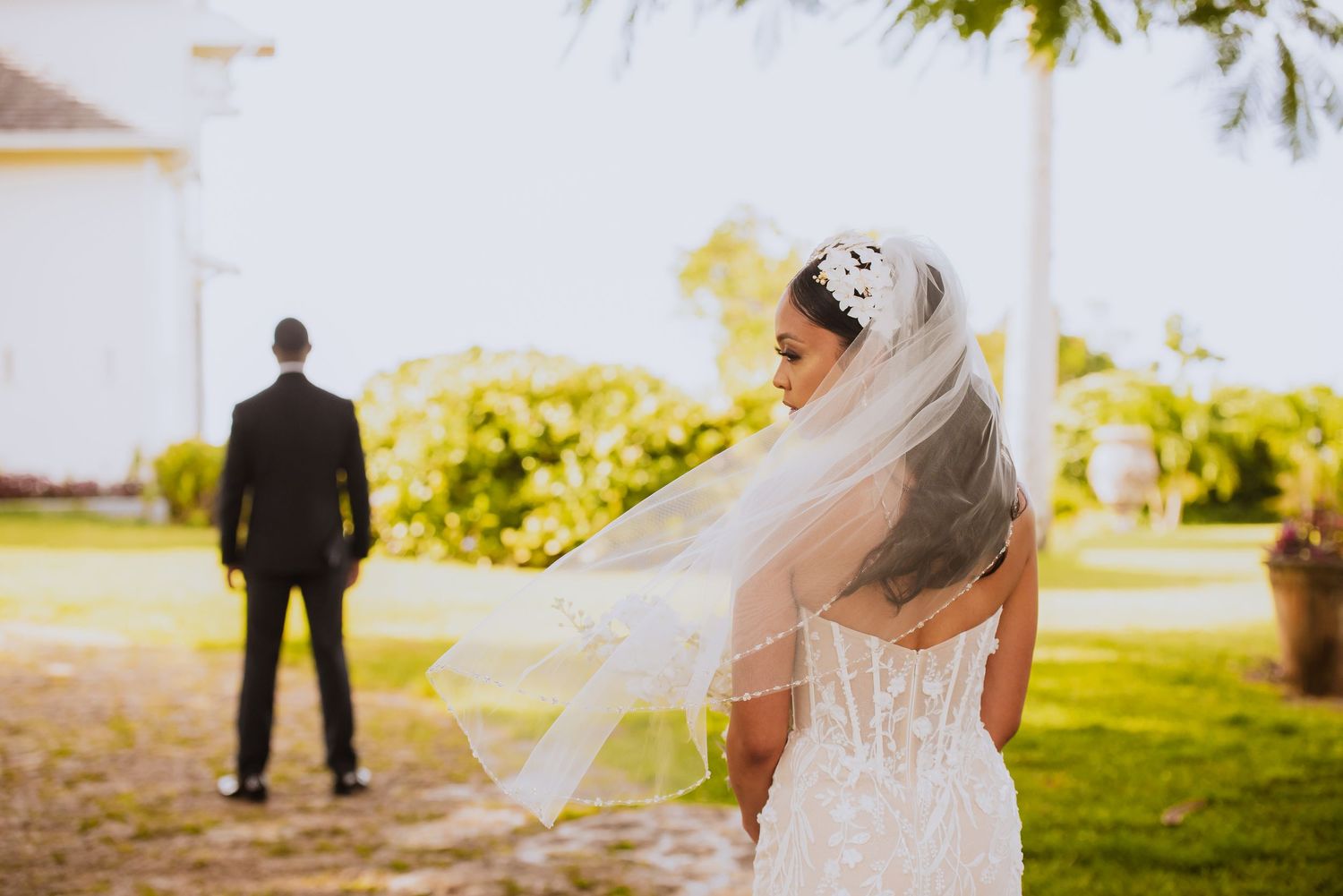 Wedding couple's first look moment captured in a sunlit outdoor garden setting.