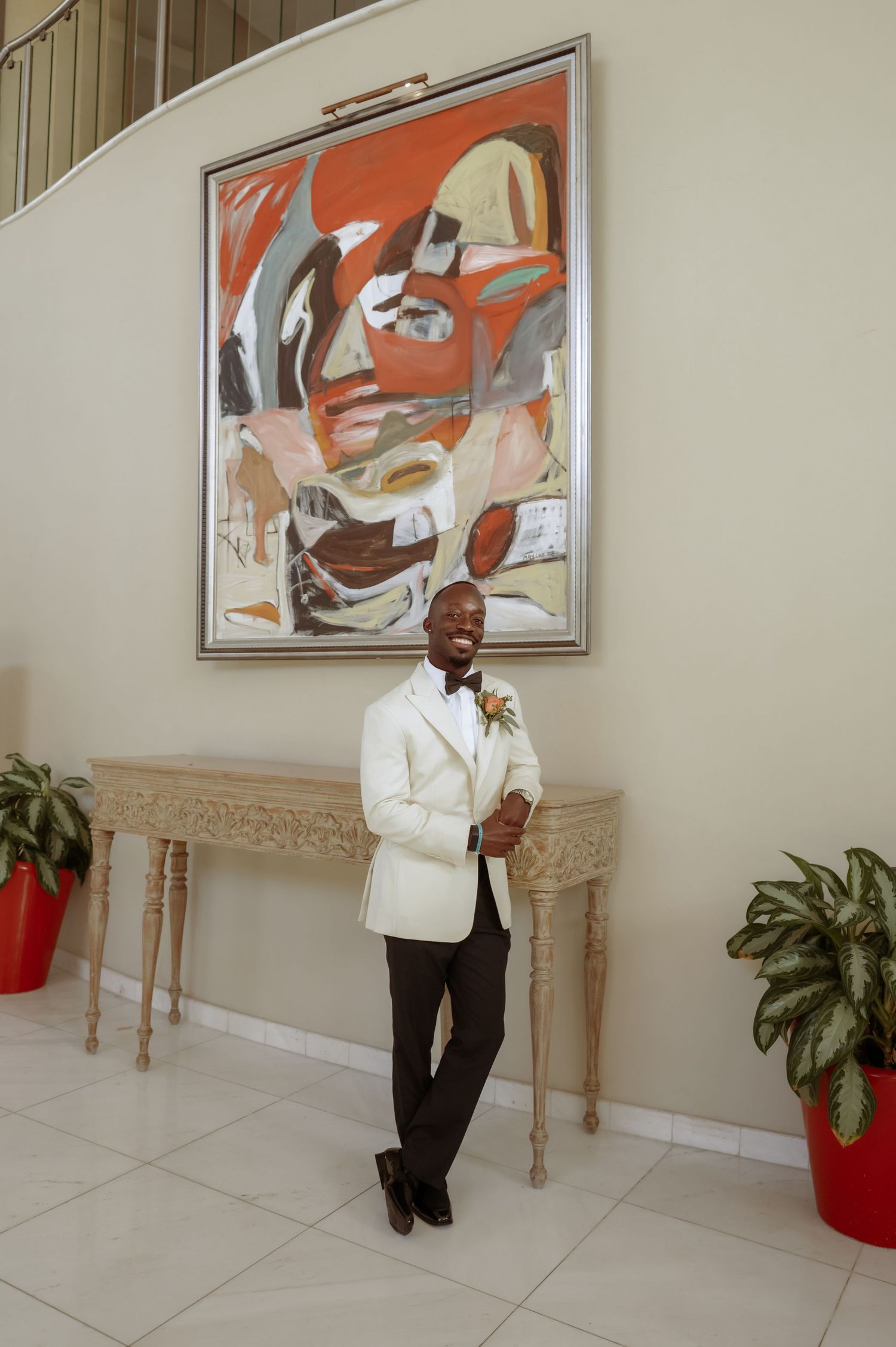 Formal portrait in white tuxedo jacket against modern abstract wall art.