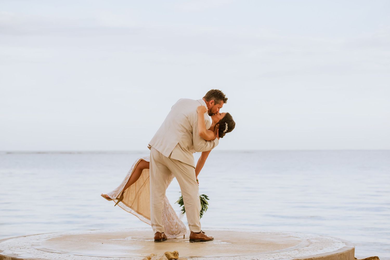 Couple executes dramatic dance dip pose during their beach wedding photoshoot.