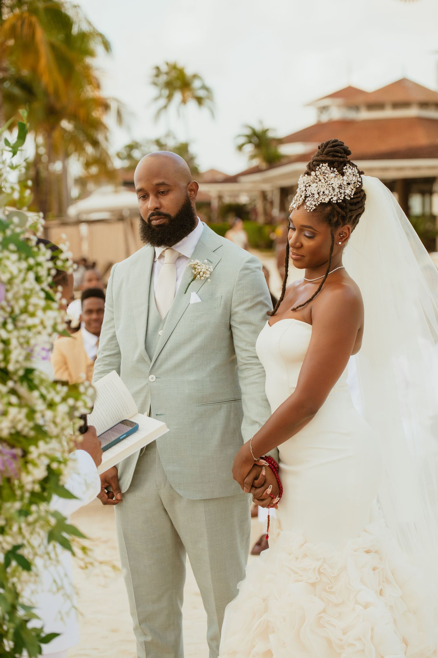 Newlyweds sharing candid moments in mint green and white attire on a tropical beach.