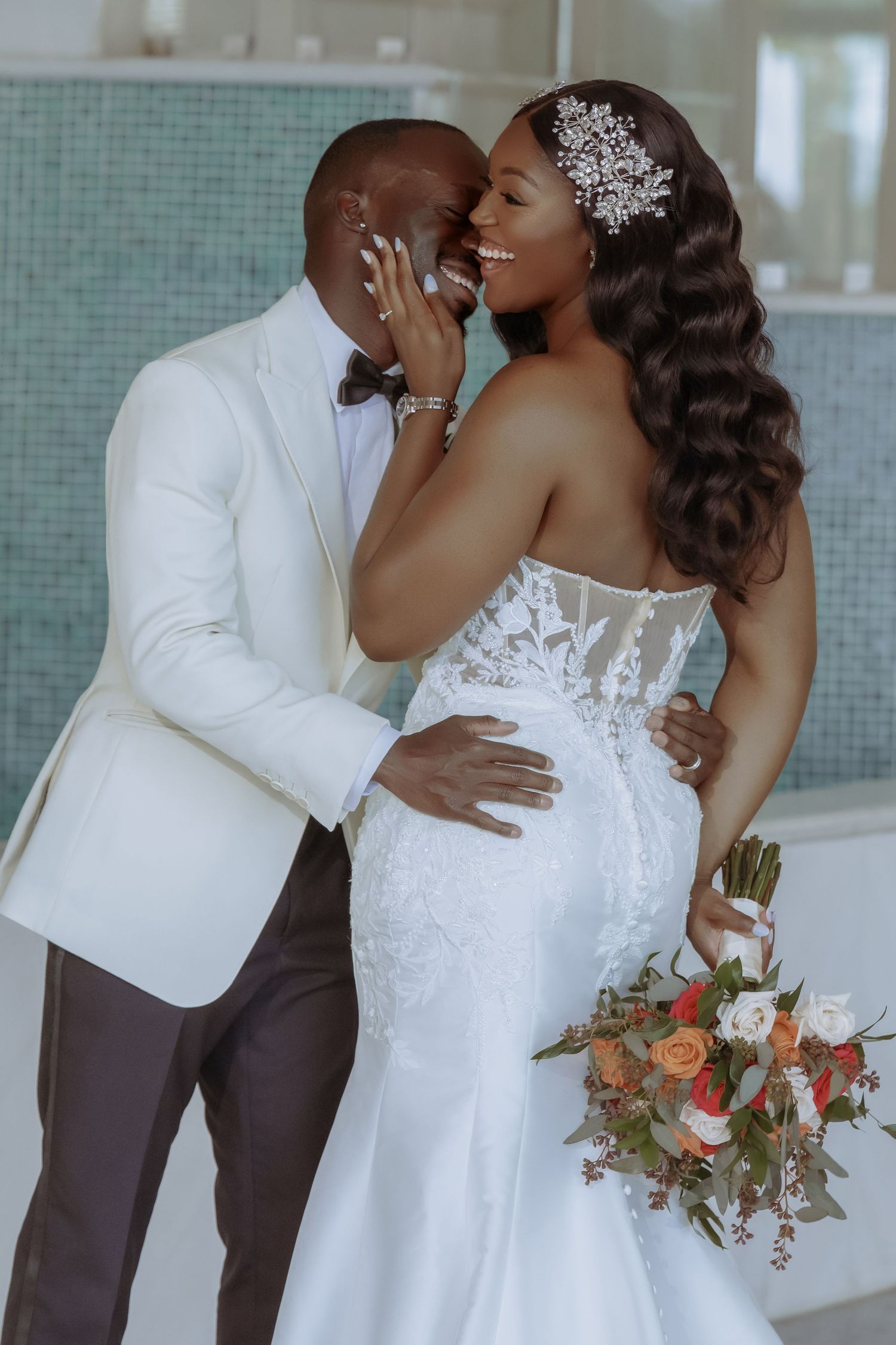 Elegant wedding couple embracing during their photoshoot with floral bouquet details.