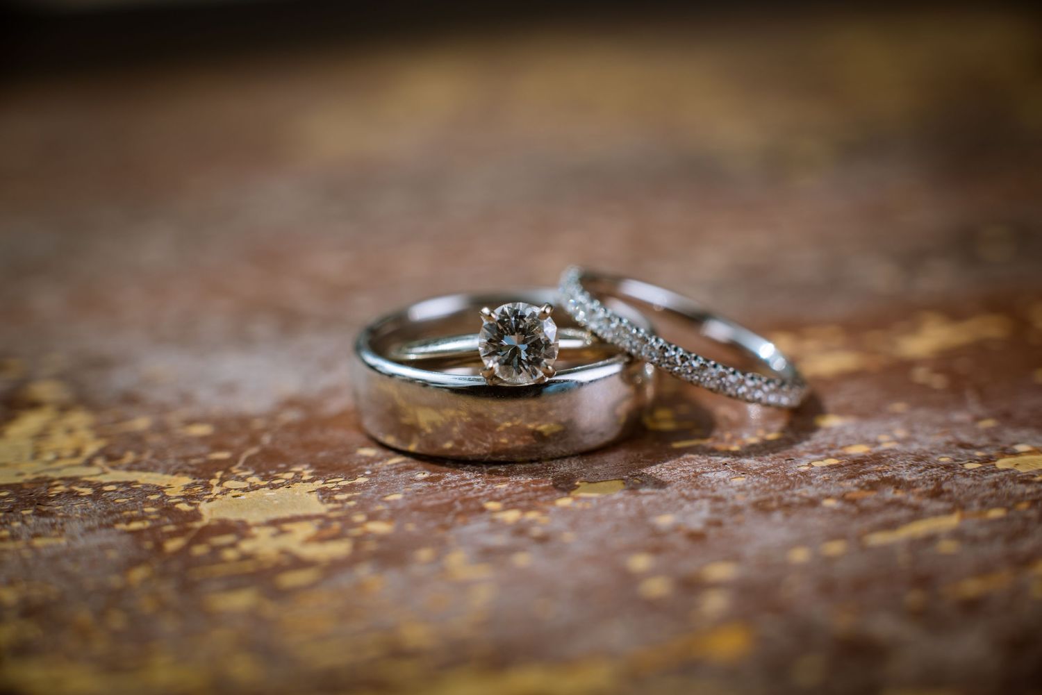 Close-up shot of wedding rings on textured rustic brown surface.