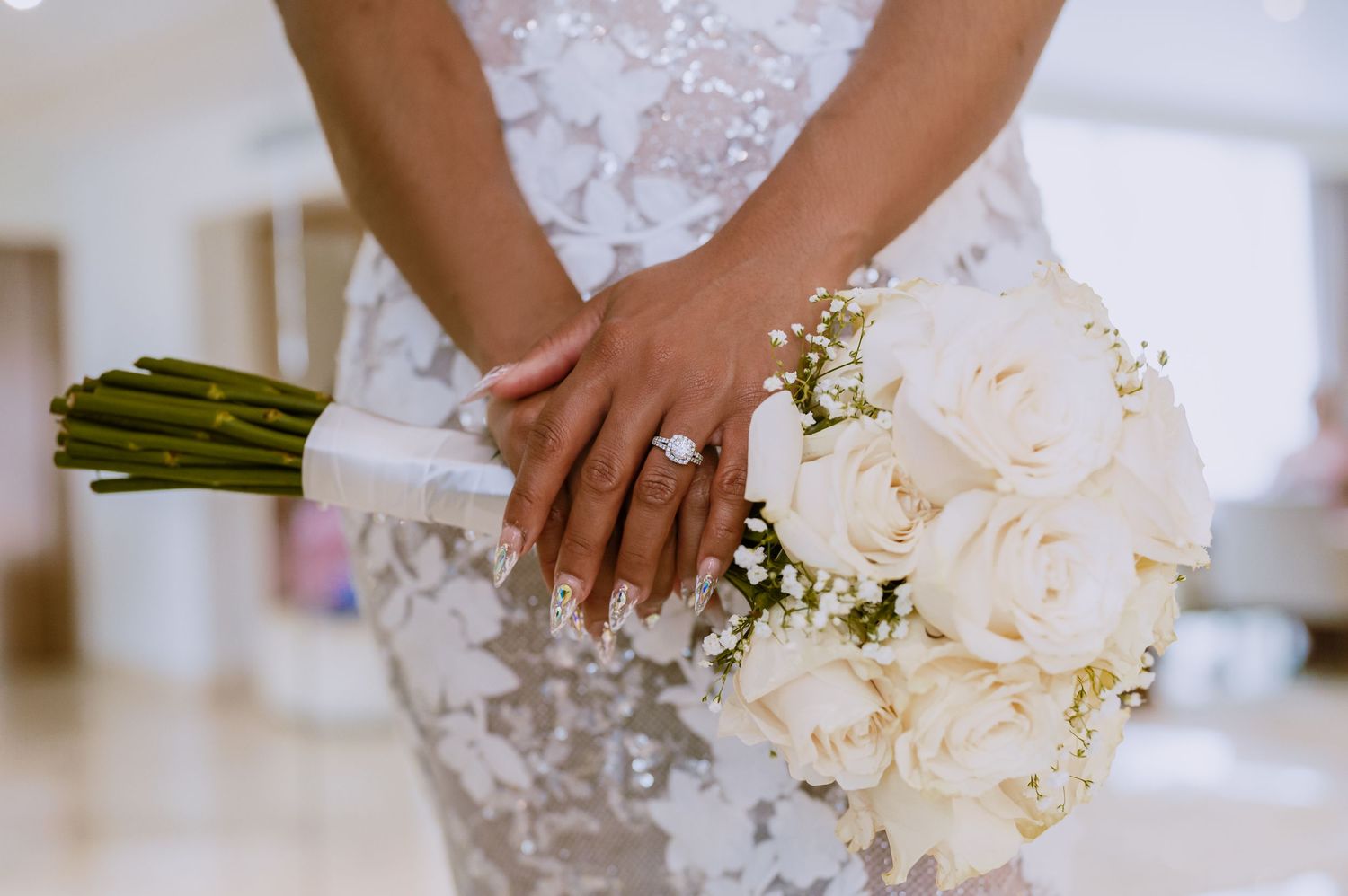 Close-up shots of hands holding an elegant white rose wedding bouquet with greenery.