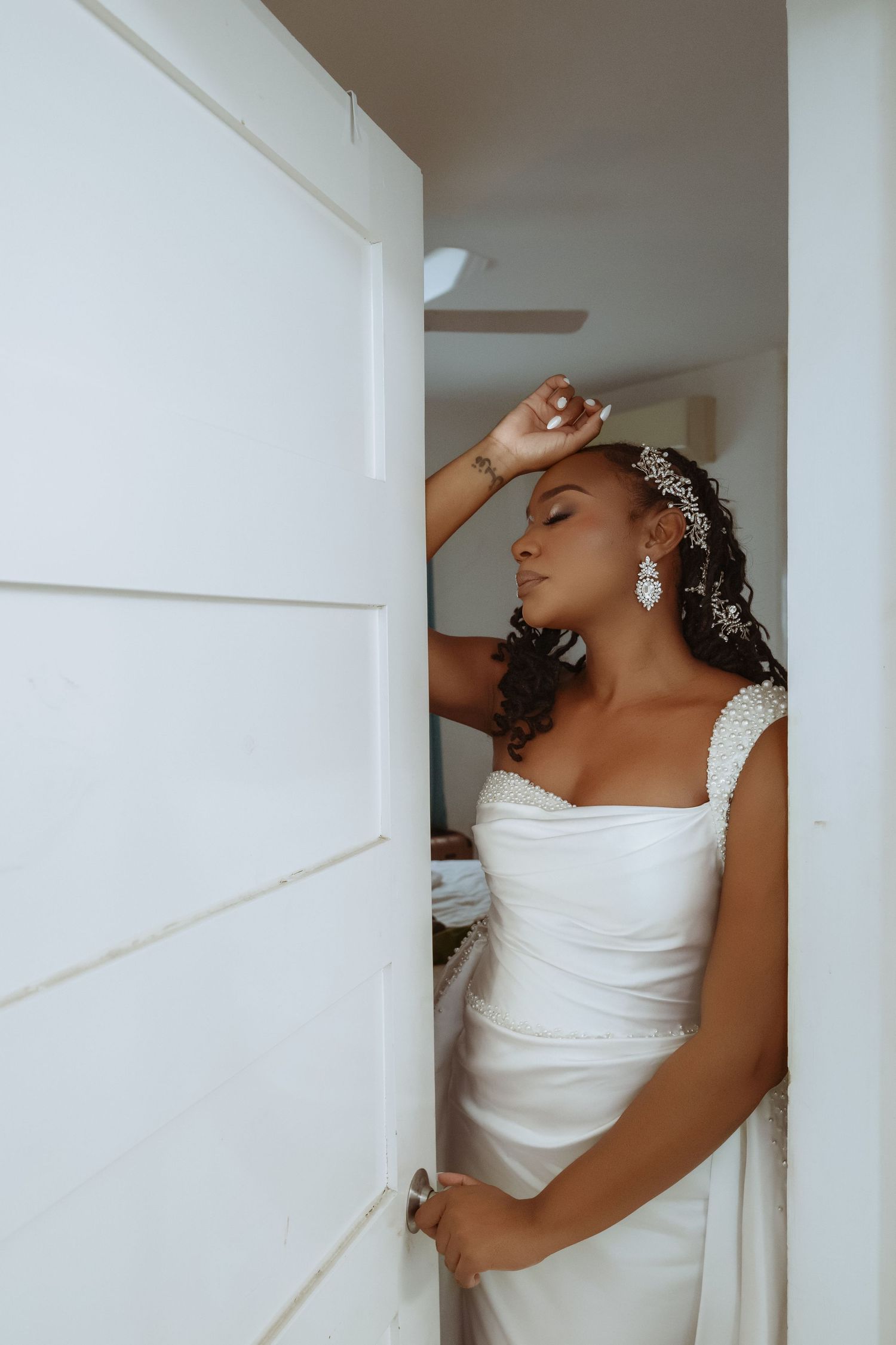 Artistic bridal portraits showing dramatic poses against white walls in an intimate indoor setting.