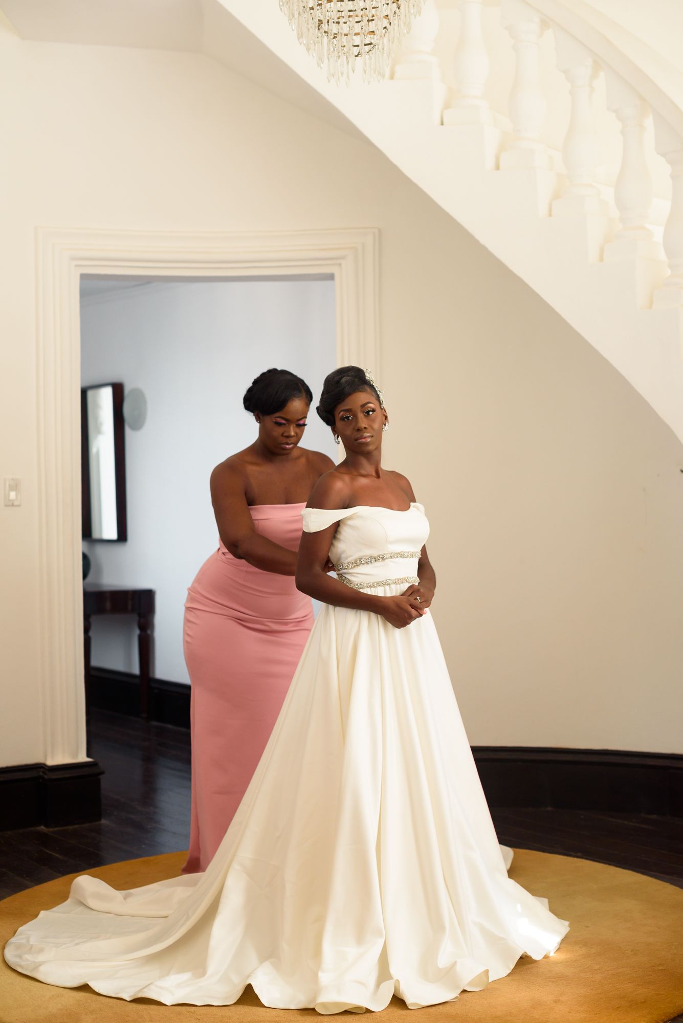 Two people share an intimate moment during a wedding dress fitting in a bright indoor space.
