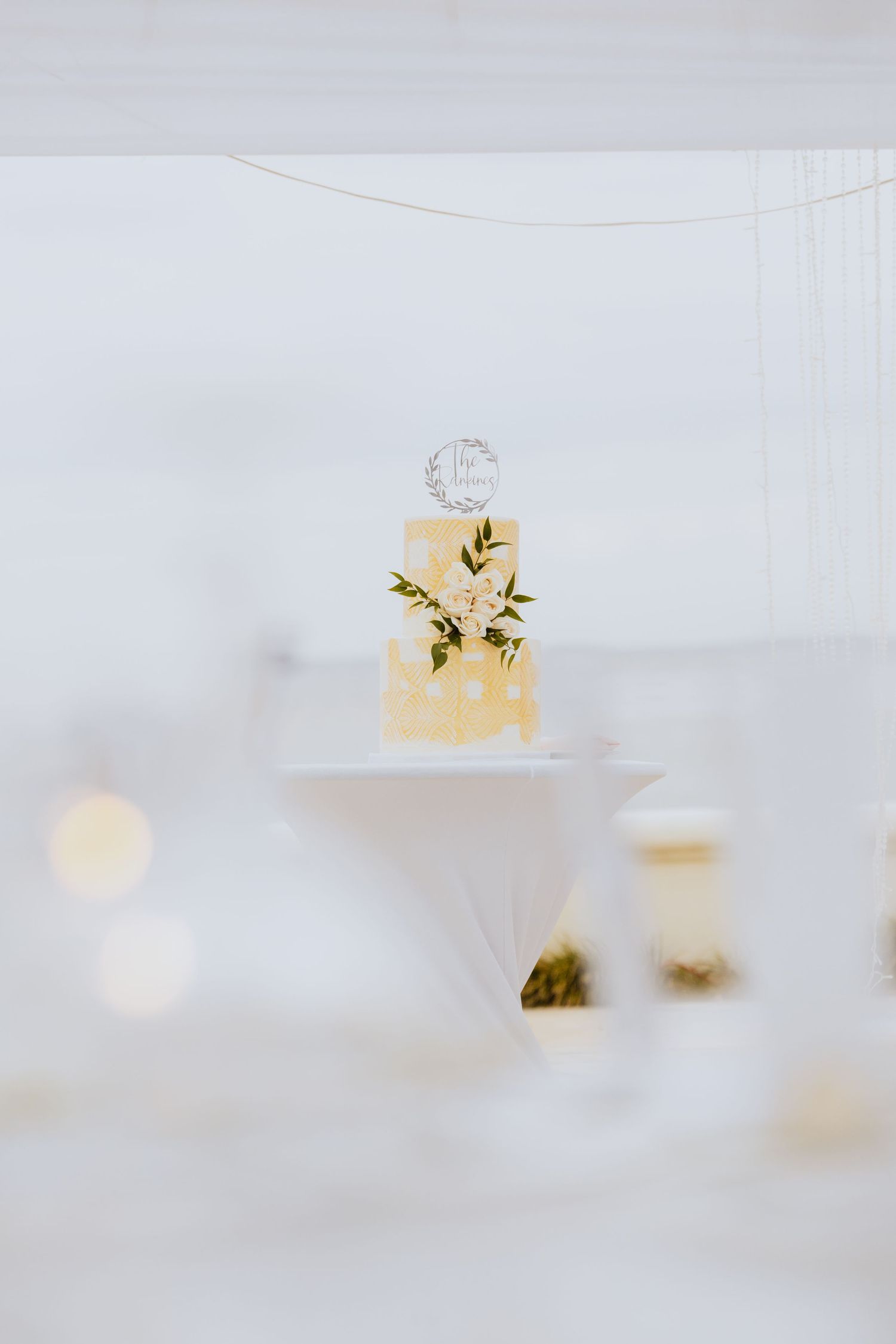Minimalist two-tier wedding cake with delicate floral accents on white background.