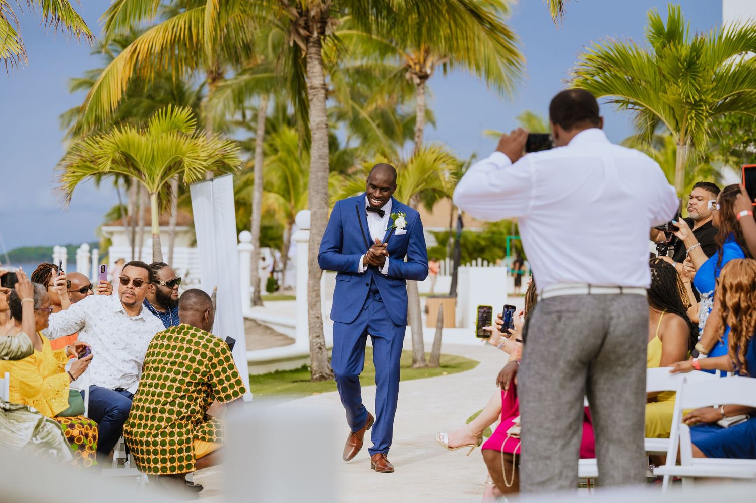 Wedding celebration with guests enjoying outdoor festivities under palm trees.