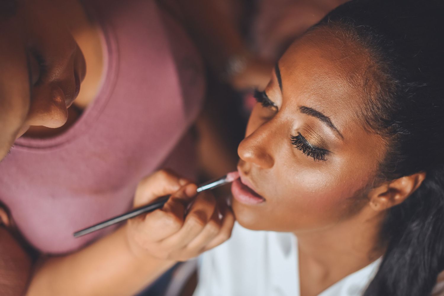 Professional makeup artist applying cosmetics and finishing touches during bridal preparation.